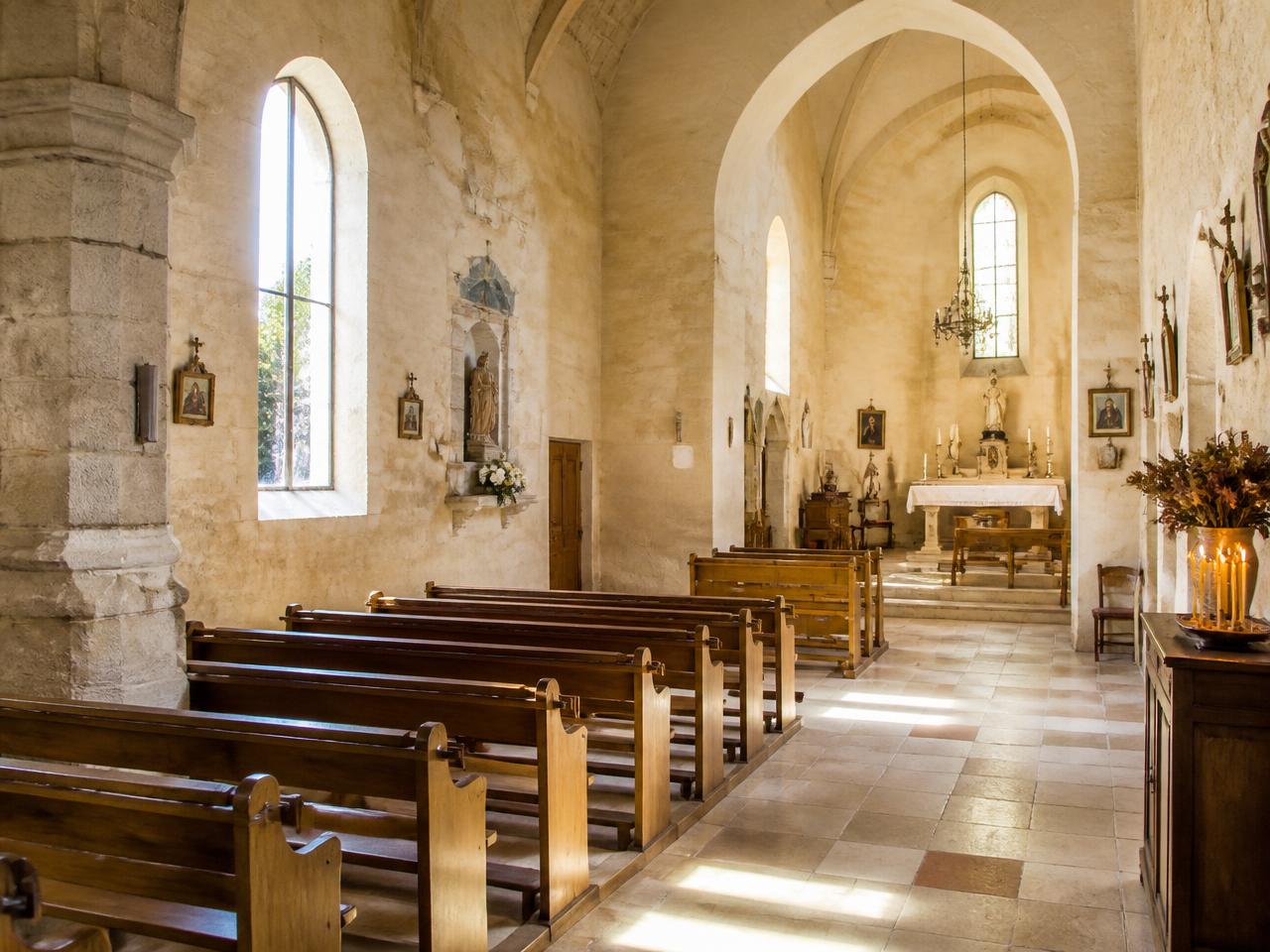 Intérieur lumineux de l'église en pierre avec ses bancs de bois